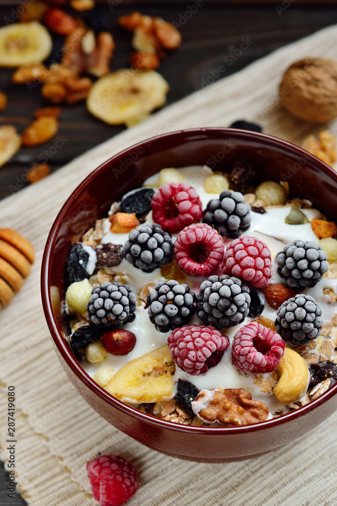 Granola with yougurt, nuts, fresh berries on wooden brown background Granola with yougurt, nuts, fresh berries on wooden brown background