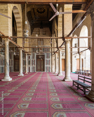 Corridor at public historic mosque of Sultan Al Moaayad, ending with colorful marble wall and wooden door decorated with arabesque ornaments, Old Cairo, Egypt photo