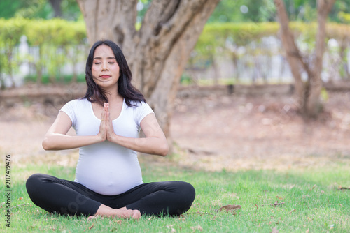 Portrait of asian Beautiful pregnant woman at the park,Thailand people,Happy woman concept,Her play yoga on the lawn