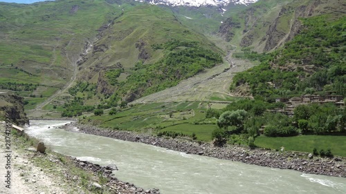 Kulob to Qalai Khumb Pamir Highway along the Panj River with View of a Village on the Afghanistan Side on a Sunny Blue Sky Day photo