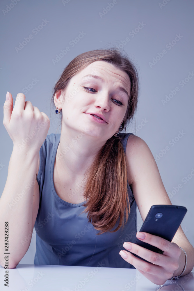 Naklejka premium Wasting time on social media. Portrait of young beautiful woman with smartphone as symbol of social Media addiction. Psychological problems and media mania concept.