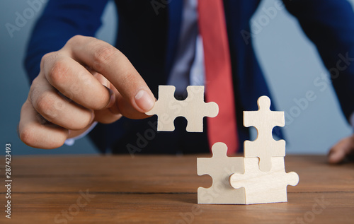 A businessman is assembling a puzzle; business concept