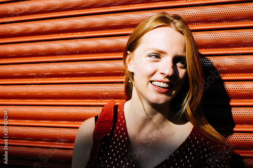 Beautiful expressive young woman in bright sun light on terracotta background  photo