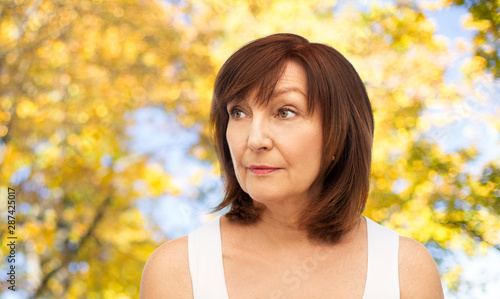 beauty and old people concept - portrait of senior woman over natural autumn background