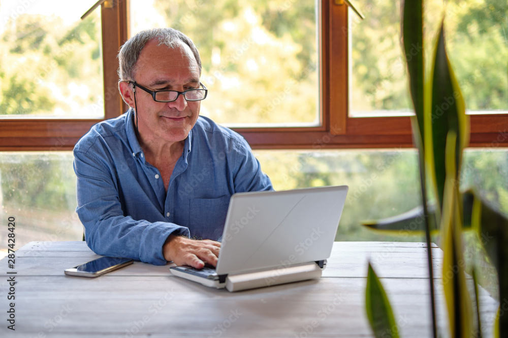 Fototapeta premium Mature man working with laptop at home