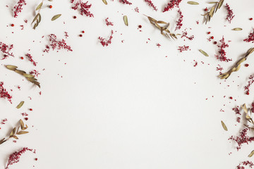 Autumn composition. Border made of red flowers, eucalyptus leaves, berries on gray background. Autumn, fall, thanksgiving day concept. Flat lay, top view, copy space