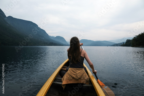 Young woman canoeing in the lake bohinj on a summer day, background alps mountains. © sztnknmi