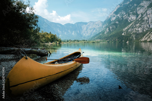 canoeing in the lake bohinj on a summer day, background alps mountains.