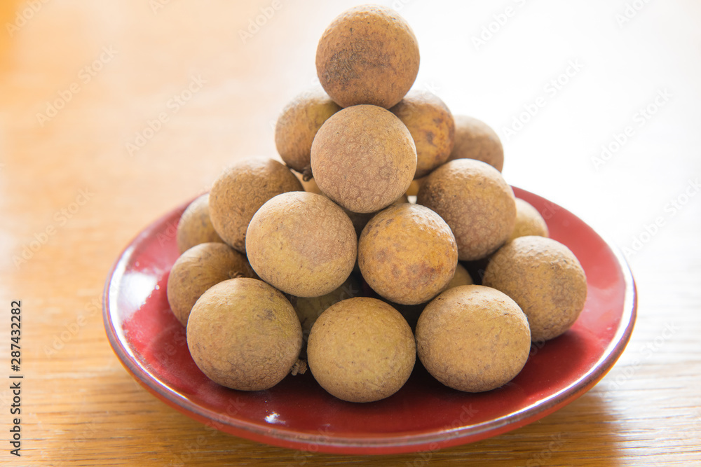 Fresh longan on a red porcelain plate isolated Fresh longan on a red porcelain plate isolated