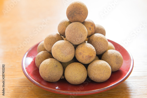 Fresh longan on a red porcelain plate isolated