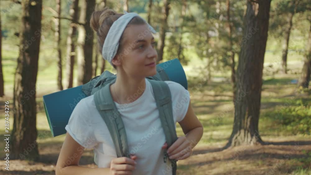 Slow motion woman tourist with backpack walking in the fall forest on sunny summer day smile look around vacation camping hiking travel wood hike active journey young nature people activity close up Slow motion woman tourist with backpack walking in the fall forest on sunny summer day smile look around vacation camping hiking travel wood hike active journey young nature people activity close up