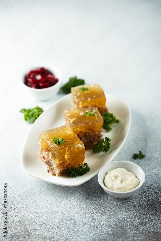 Festive meat jelly with sauces on white plate Festive meat jelly with sauces on white plate