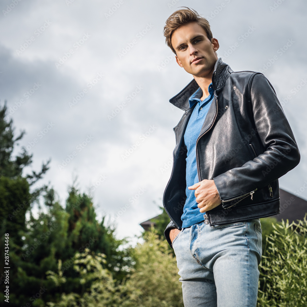 Young handsome man in classic leather jacket pose in summer garden. foto de  Stock | Adobe Stock