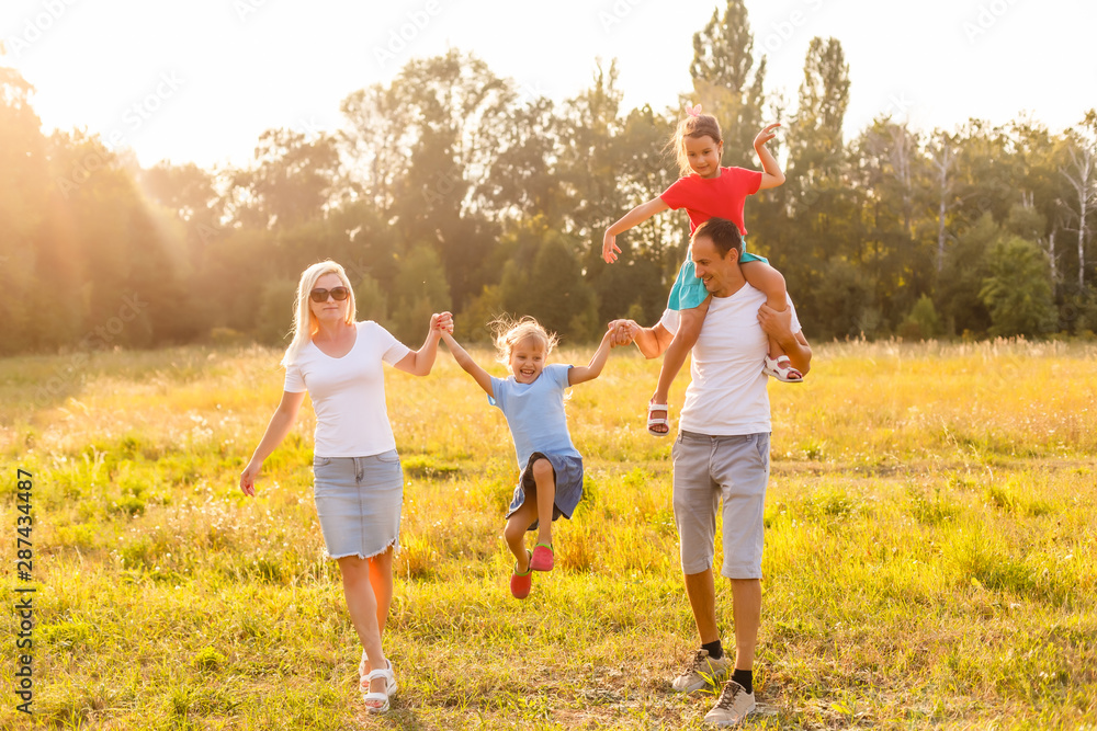 Fototapeta premium young familiy running through a yellow field