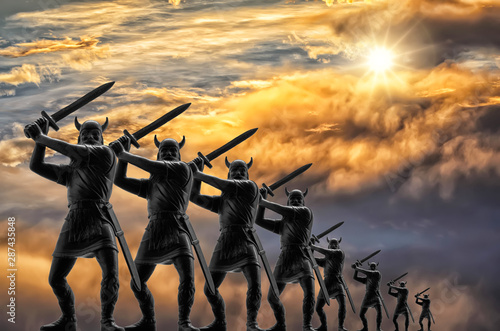 Eight Vikings (plastic toy soldiers) with raised swords arrayed in a line in attack, sky with stormy clouds and bright sun, vanishing point effect, Old Norse myths, Valhalla, Ragnarok and Odin themes
