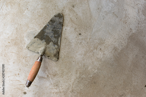 Construction tool for repairing trowels lies on gray-brown cement and concrete photo