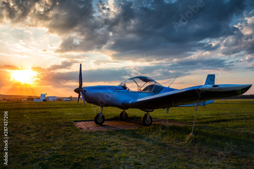 A small sports airplane parked at the airfield at scenic sunset
