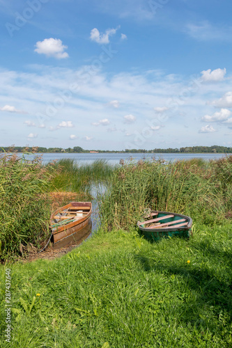 Fototapeta Naklejka Na Ścianę i Meble -  Wooden boats, old fishing vessels on the coast of tranquil lake, sustainable ecological tourism in Europe