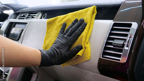 A woman at a car wash does a full dry-cleaning of all parts of a car using special chemistry, cloths, sponges and brushes. Concept of: Full car cleaning, Dry cleaning, Professional service. Car, Work. © dkHDvideo