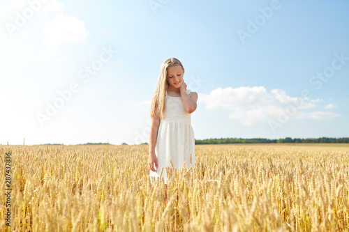 nature, harvest and people concept - smiling young girl on cereal field in summer