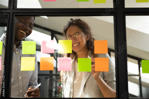 Two diverse happy team people working together with sticky notes