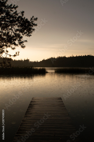 Steg am See bei Regen im Sonnenuntergang