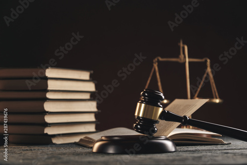 Law concept - Open law book with a wooden judges gavel on table in a courtroom or law enforcement office on black background.