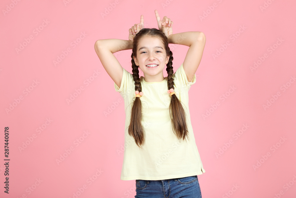 Beautiful young girl showing ears by hands on pink background Beautiful young girl showing ears by hands on pink background