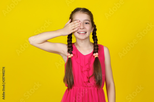 Beautiful young girl in pink dress on yellow background