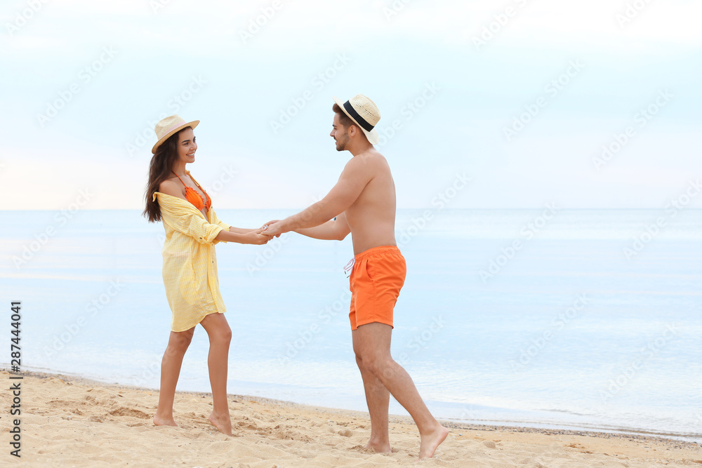 Happy young couple spending time together on beach near sea Happy young couple spending time together on beach near sea
