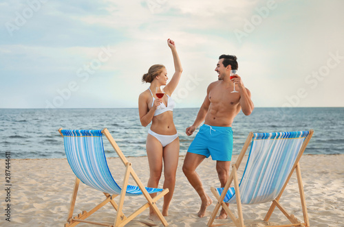 Happy young couple dancing near deck chairs at sea beach © New Africa