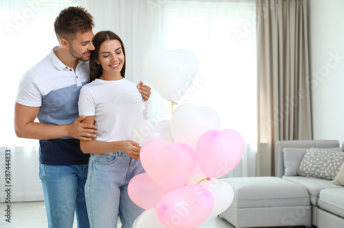 Young couple with air balloons at home. Celebration of Saint Valentine's Day