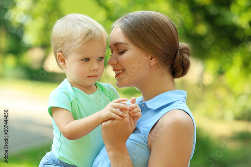 Young mother with her cute child in green park