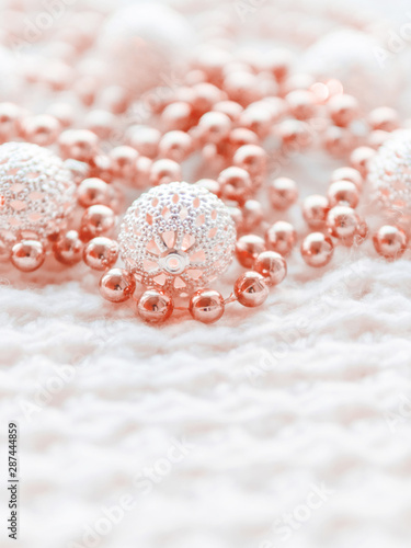 Christmas and New Year decorations on white knitted background. Metal light bulbs with delicate pattern, light red beads.