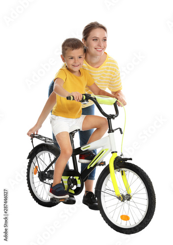 Young mother teaching son to ride bicycle on white background