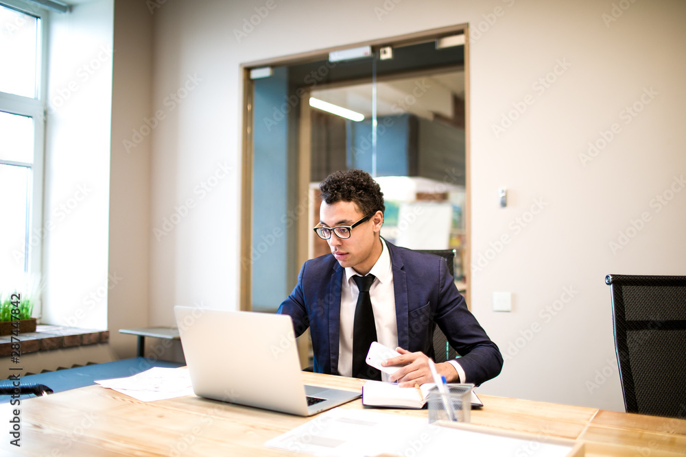 Intelligent man leadership searching new employee in internet via laptop computer while sitting in office big successful company. Male in suit and glasses skilled entrepreneur reading news via netbook Intelligent man leadership searching new employee in internet via laptop computer while sitting in office big successful company. Male in suit and glasses skilled entrepreneur reading news via netbook