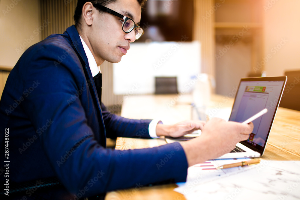 Man professional business worker reading notifications on mobile phone, sitting at workplace with laptop computer. Male in suit successful employer typing text on cellphone during using notebook Man professional business worker reading notifications on mobile phone, sitting at workplace with laptop computer. Male in suit successful employer typing text on cellphone during using notebook