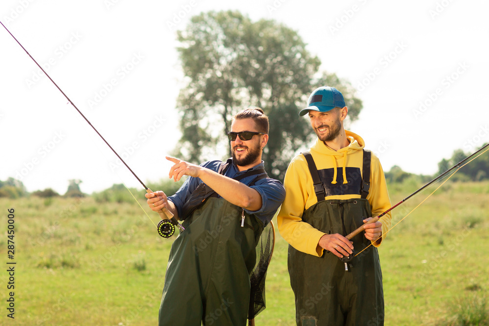 Two fishermen preparing for fishing. They hold the fishing rods and talk to each other. Sport fishing Two fishermen preparing for fishing. They hold the fishing rods and talk to each other. Sport fishing