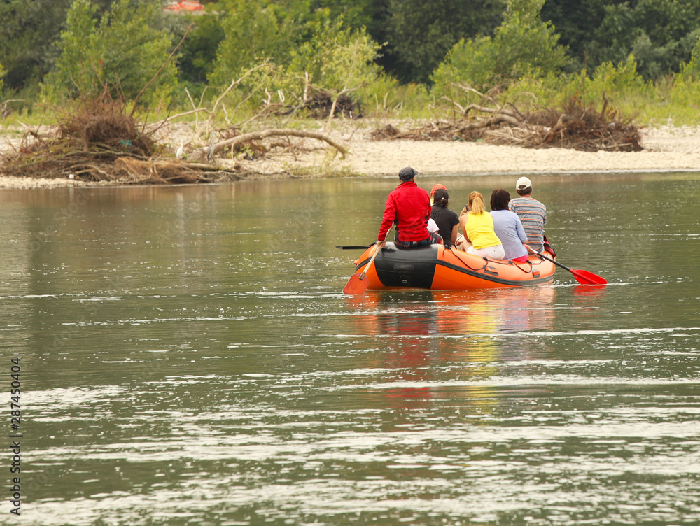 A group of tourists rafting on a mountain river on a pontoon. Tourist routes of Transcarpathia in Ukraine. Rafting on the Tissa River. Safety on the water. Lifeboat and the man behind the bot - MOB. A group of tourists rafting on a mountain river on a pontoon. Tourist routes of Transcarpathia in Ukraine. Rafting on the Tissa River. Safety on the water. Lifeboat and the man behind the bot - MOB.