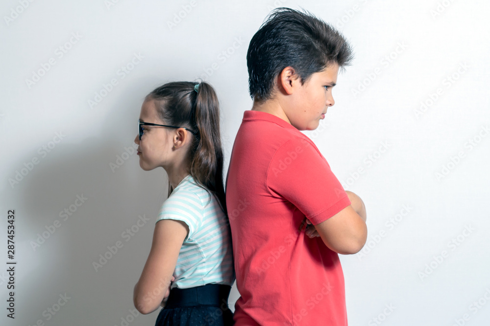 The boy resents the little girl. Children stand with their backs to each other. Brother and sister disappointed The boy resents the little girl. Children stand with their backs to each other. Brother and sister disappointed