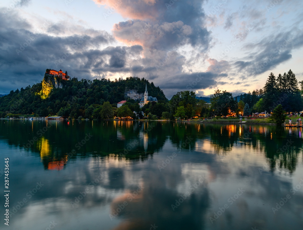 Fototapeta premium Evening (blue hour) landscape on Lake Bled with reflection and beautiful cloudy sky.
