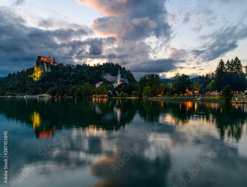 Evening (blue hour) landscape on Lake Bled with reflection and beautiful cloudy sky.