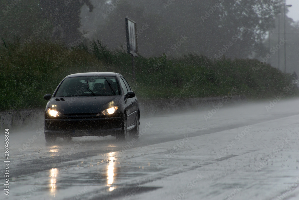 The strong storm with heavy rain on the road with poor visibility of cars. Concept of the danger of driving in bad weather