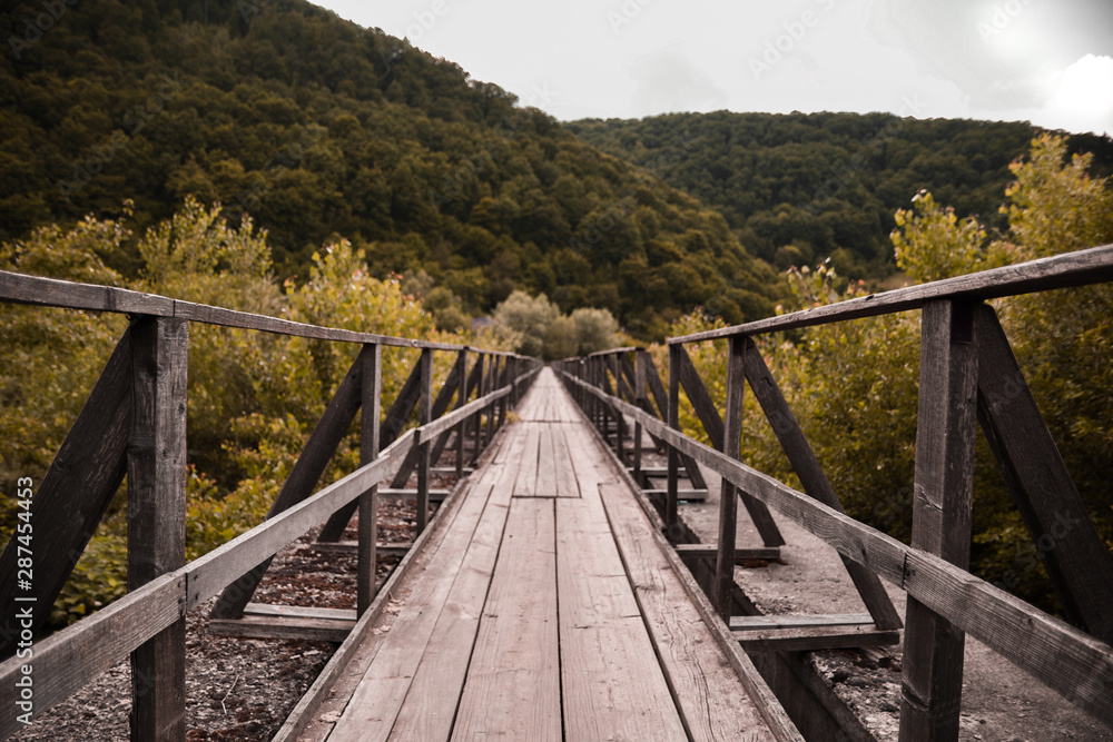 Winding wooden bridge over a river old in deep forest, natural vintage background Winding wooden bridge over a river old in deep forest, natural vintage background
