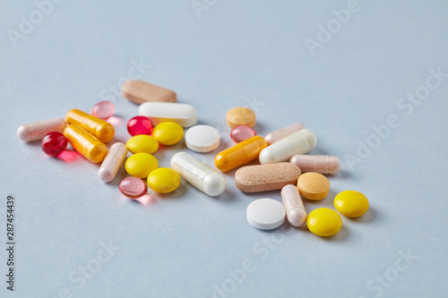 Vitamins and supplements on bright paper background. Concept for a healthy dietary supplementation. Close up. Copy space. 