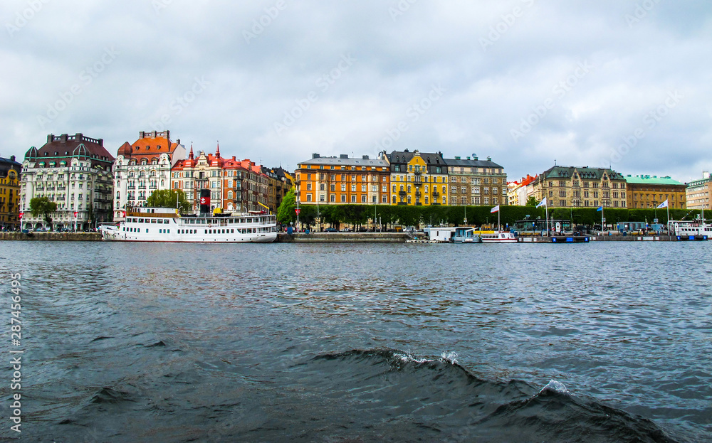 Panoramic view from the tourist boat on the pier with boats and the beautiful buildings of Stromkayen in the center of Stockholm Sweden