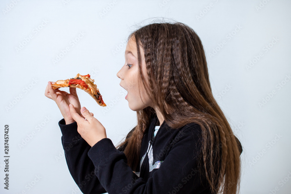 Little girl eating pizza. Baby puts pizza in her mouth