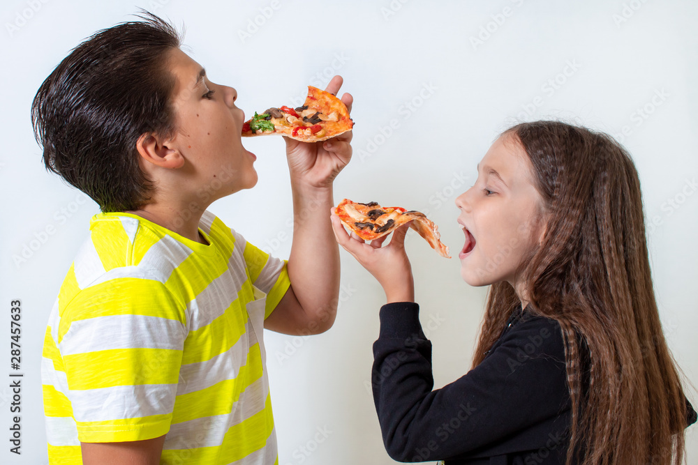 Little boy and girl eating pizza. The children have lunch Little boy and girl eating pizza. The children have lunch