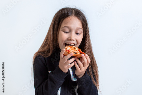 Little girl eating pizza. Baby puts pizza in her mouth