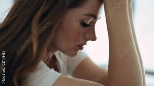 Sad face young woman sitting cries at home indoors at sunlight depression nervous charming attractive female girl modern close up slow motion photo